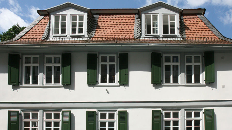 Frisch in weiß gestrichenes Pfarrhaus mit grünen Fensterläden 