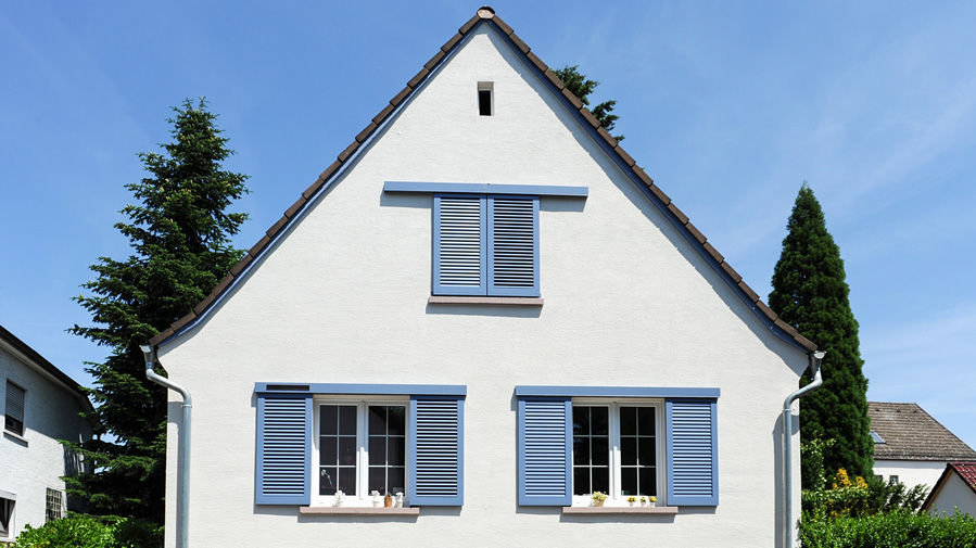 Neuer weißer Putz für Einfamilienhaus mit blauen Fensterläden